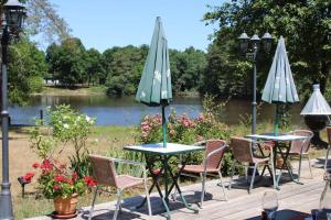 a group of tables and chairs with umbrellas in front of a lake at Détente au golf des etoiles in Nançay
