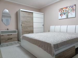 a white bedroom with a bed and a sink at Apartament Serenity in Băile Herculane