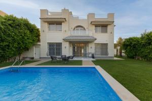 a house with a swimming pool in front of it at Warm family palace with garden and pool in Royal City in Sheikh Zayed