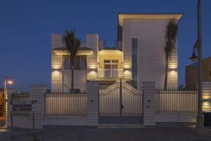 a white house with a fence in front of it at Warm family palace with garden and pool in Royal City in Sheikh Zayed