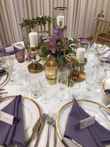 une table avec des serviettes violettes et des assiettes dorées dessus dans l'établissement Majoro sodyba,  8 autres photos