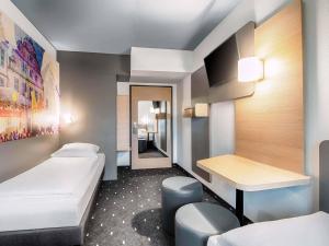 a small room with two beds and a desk at B&B Hotel Bielefeld-Ost in Bielefeld