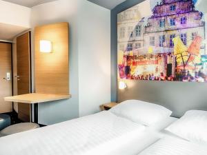 ビーレフェルトにあるB&B Hotel Bielefeld-Ostのベッドが2つあり、壁に絵が飾られた寝室