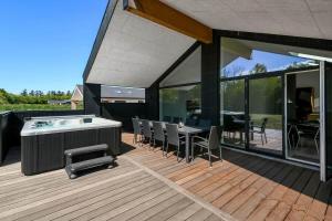 una terrazza con vasca idromassaggio, tavolo e sedie. di C11642-Bork-Nordmarken-3 a Falen