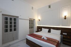 a bedroom with a large bed with white sheets at Bhawani Homes in Varanasi