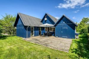 a blue barn with a wooden deck in the yard at C11693-Hemmet-Bork-Hytteby-144 in Falen