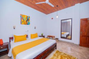 a bedroom with a large bed with yellow pillows at Villa Comfort in Hikkaduwa