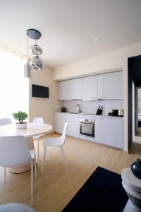 a kitchen with white cabinets and a table and chairs at Premier Stay The Garden - Bernina Experience in Tirano