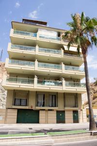 a tall building with a palm tree in front of it at Apartamento Carvajal Fuengirola in Fuengirola