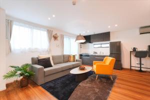 a living room with a couch and an orange chair at Tomo House 四谷三丁目 301 in Tokyo