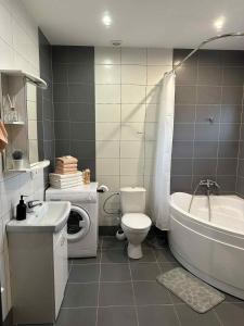 a bathroom with a toilet and a tub and a sink at Modern apartment with balcony in Užliedžiai +19 photos