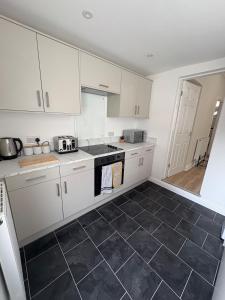 a kitchen with white cabinets and a black tile floor at Modern House Great Location in Hull +8 photos