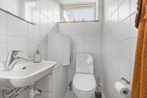 a white bathroom with a toilet and a sink at 84237-Knebel-Skovvej-18 in Skødshoved Strand +12 photos