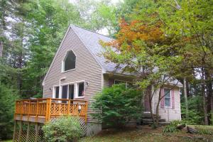 a white house with a porch in the woods at Lincolnville 2BR - Beach Vibes & Backyard BBQ in Lincolnville