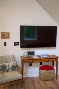 a living room with a table with a television on a wall at Lincolnville 2BR - Beach Vibes & Backyard BBQ in Lincolnville +38 photos