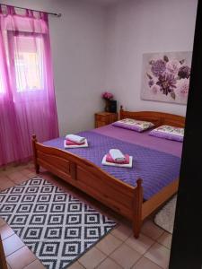 a bedroom with a bed with purple sheets and a window at DosPalmeras in Vir