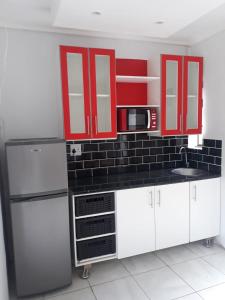 a kitchen with red cabinets and a sink and a microwave at Barrymicasa Self Catering in Gqeberha