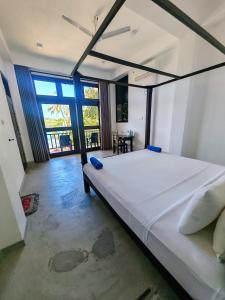 a bedroom with a large bed in a room with large windows at Waves Hiri Sea View in Hiriketiya