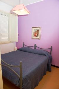 una camera con un letto con una parete viola di Lomarchi Holiday Home a Carini