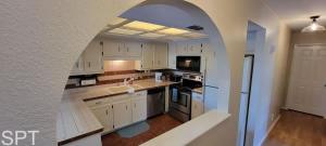 a kitchen with white cabinets and an archway in it at Large 3 bedr Bay Views Pool Great Deck condo in South Padre Island