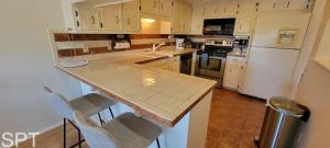 a kitchen with white appliances and a counter with chairs at Large 3 bedr Bay Views Pool Great Deck condo in South Padre Island