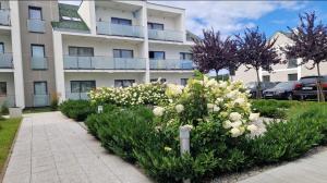 a flower garden in front of a building at Apartament Piaskowy Sunset Resort in Grzybowo
