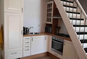 a kitchen with white cabinets and a spiral staircase at Zilte zee Ameland in Buren +10 photos