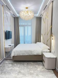 a bedroom with a large bed and a chandelier at AsiaWay Apartment-Tashkent City in Tashkent