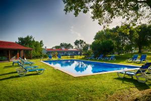 una gran piscina con sillas azules y una casa en Monte Da Galrixa, en Zambujeira do Mar