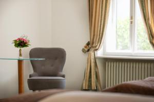 a bedroom with a chair and a table and a window at Hotel Bergwirt Schönbrunn in Vienna