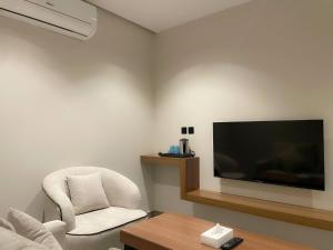 a living room with a chair and a flat screen tv at شقق خاصة بالقرب من برج الفيصلية in Riyadh