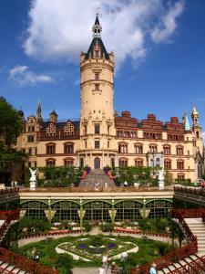 a building with a clock tower with a garden in front at Hotel am Schloß in Schwerin
