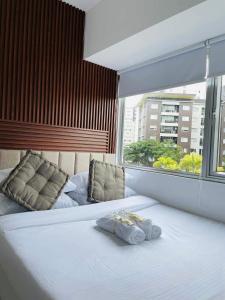 Un dormitorio con una gran cama blanca con ventana. en Spacious Two Bedroom with Pool View - Iloilo, en Iloilo City