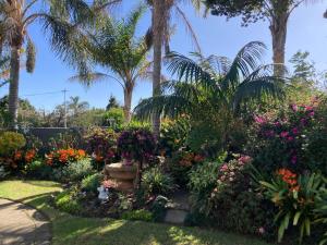 a garden with colorful flowers and palm trees at Bollinger Guest House in George