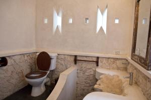 a bathroom with a toilet and a tub and a sink at Mandarina Beach House in Lamu