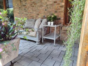 a patio with a couch and a table with plants at Serendipity Garden Studio Gateway to Kruger and Panorama Route in Kampersrus AH +18 photos