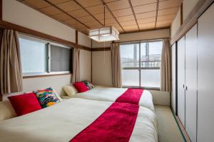 a bedroom with two beds and two windows at 成田空港直通で97平米で13名宿泊駅徒歩11分の日本スタイル in Yachiyo