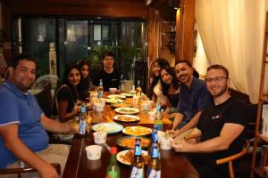 a group of people sitting around a wooden table at Happy Dragon Courtyard Hotel Beijing Forbidden City Lama Temple in Beijing