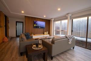 a living room with two couches and a tv at Pool, Games & fun - Family Retreat! in Boronia