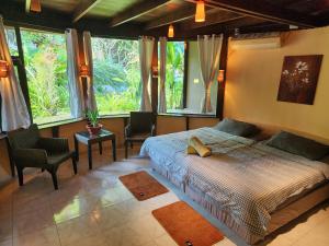 a bedroom with a bed and two chairs and windows at RELAX ECO Life Center-Khao Lak in Khao Lak +88 photos