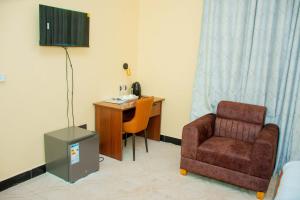 a room with a chair and a desk with a phone at Golden Tours Hotel in Dodoma