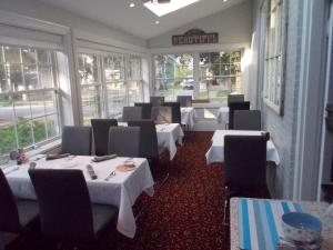 a restaurant with white tables and chairs and windows at Seaway Manor B&B in Gananoque