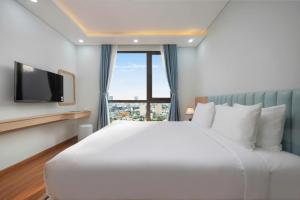 a bedroom with a large white bed and a window at Hummer Hotel & Apartment Da Nang Beach in Da Nang