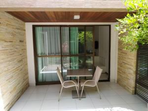 a patio with a table and chairs and a window at Bloco X - Studio 006 in Barra de São Miguel