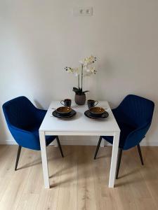 una mesa blanca con 2 sillas y un jarrón con flores en Grote Markt suite 3, en Amberes
