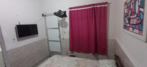 a bathroom with a red shower curtain and a television at Residencial Barbosa - Apto 102 in Macaé