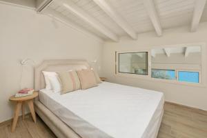 a white bedroom with a white bed and a window at Valtes Green by Vintage Travel in Corfu +36 photos
