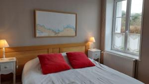 a bedroom with a bed with two red pillows on it at Cap 1 in Carneville