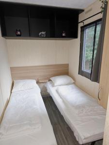 two beds in a small room with a window at Cottage no 105 auf 5 star Camping in Mariënberg