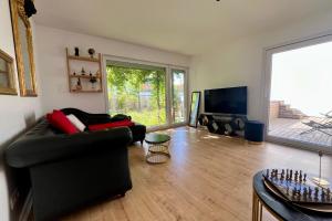 un soggiorno con divano nero e TV di Maison moderne proche Nancy 2 chambres 2 SDB parking a Seichamps
